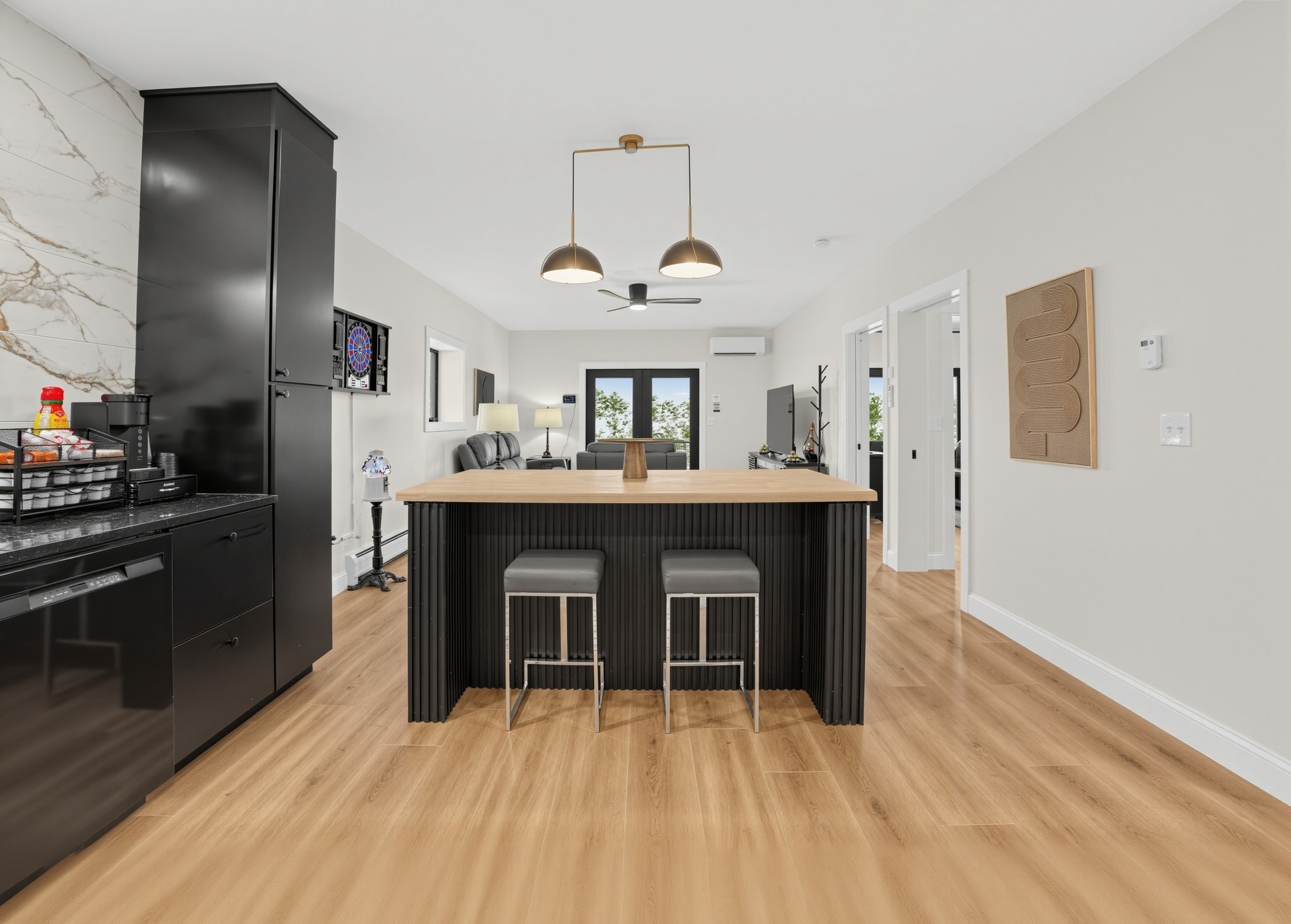 Bar area with black island, wood top, and brass pendant lights