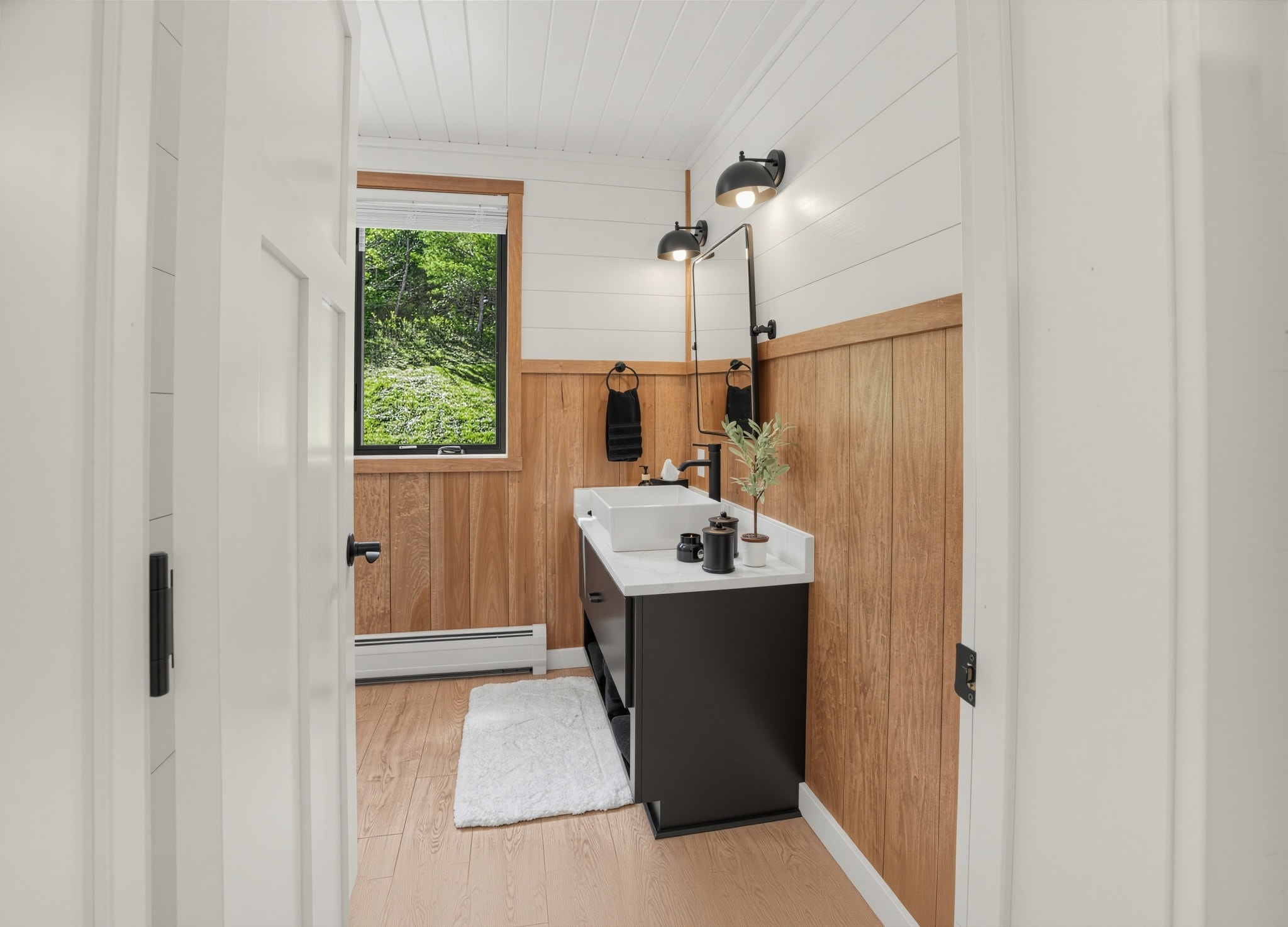Guest bathroom with wood paneling and black vanity