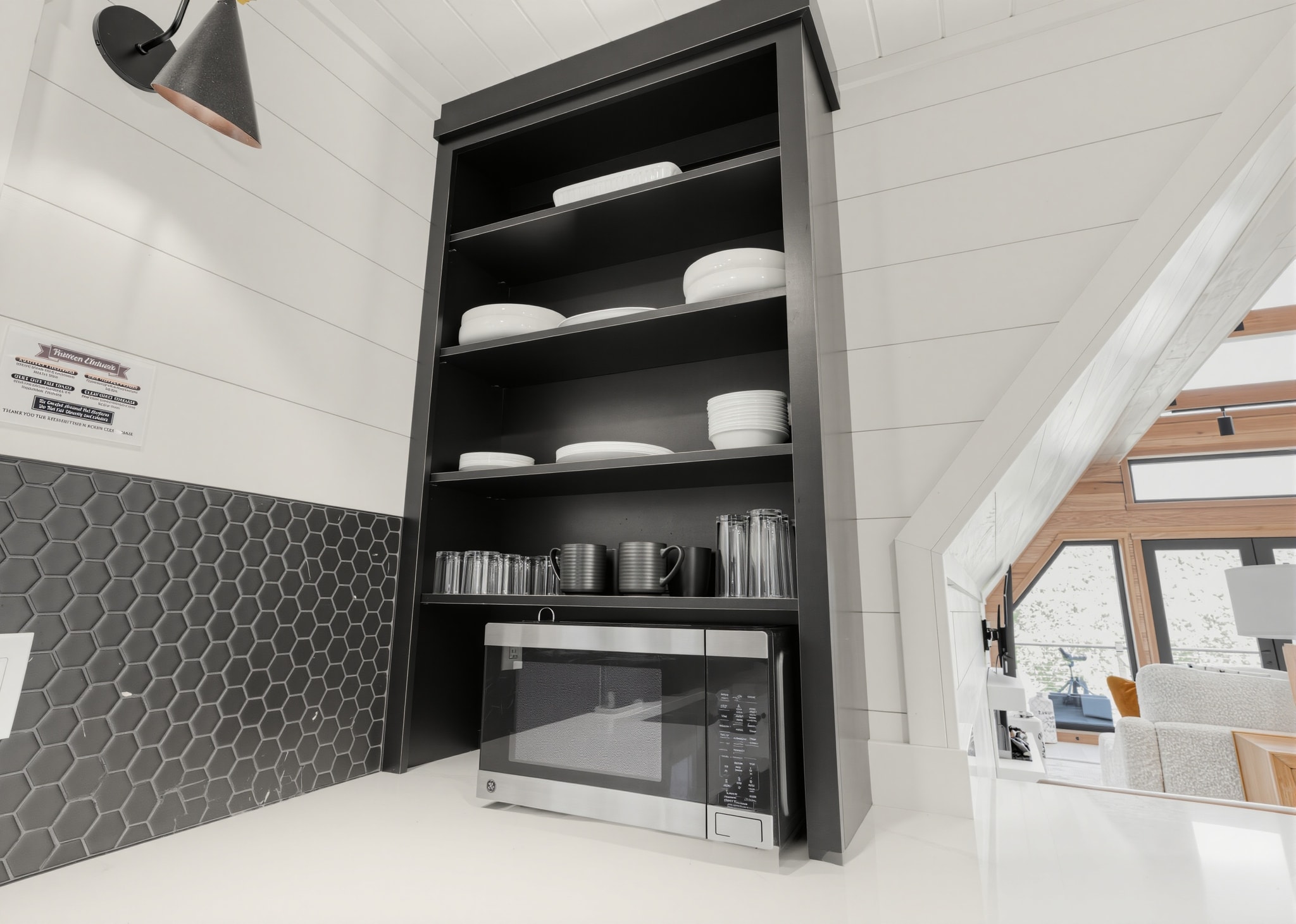 Open kitchen shelving with dishware and microwave